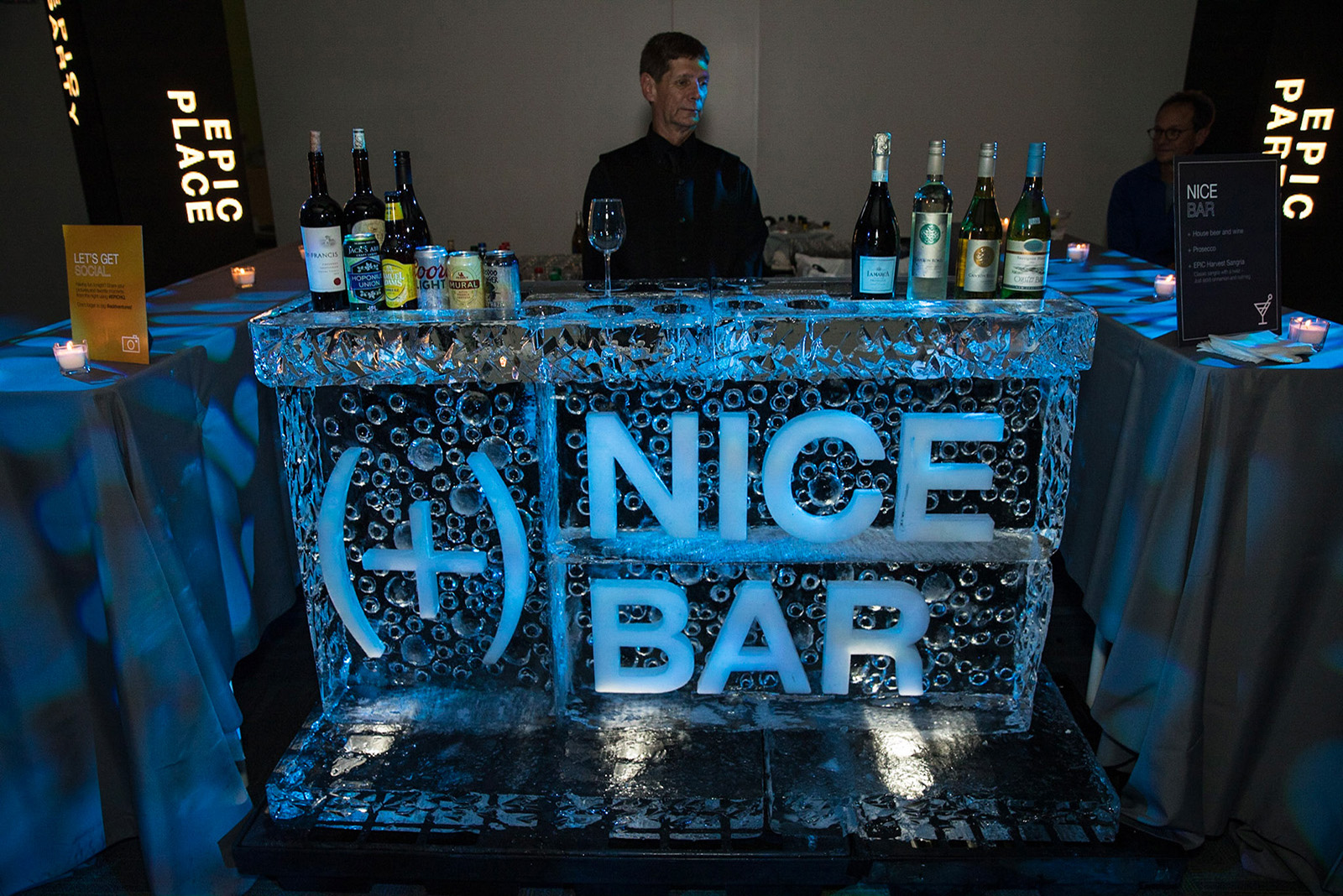 A bar made of a block of ice with a bartender behind it.