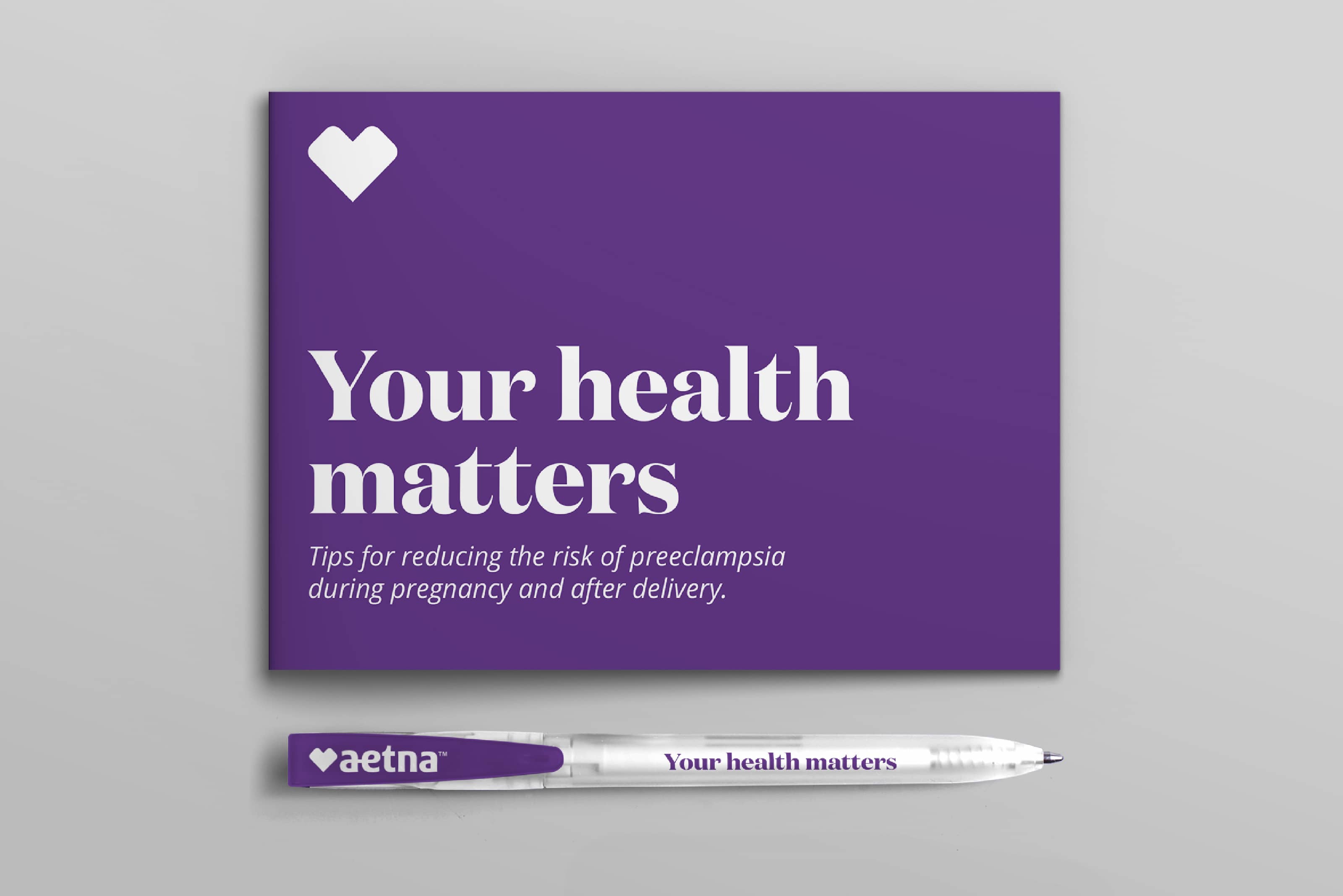 A booklet and a pen, designed with Aetna company branding