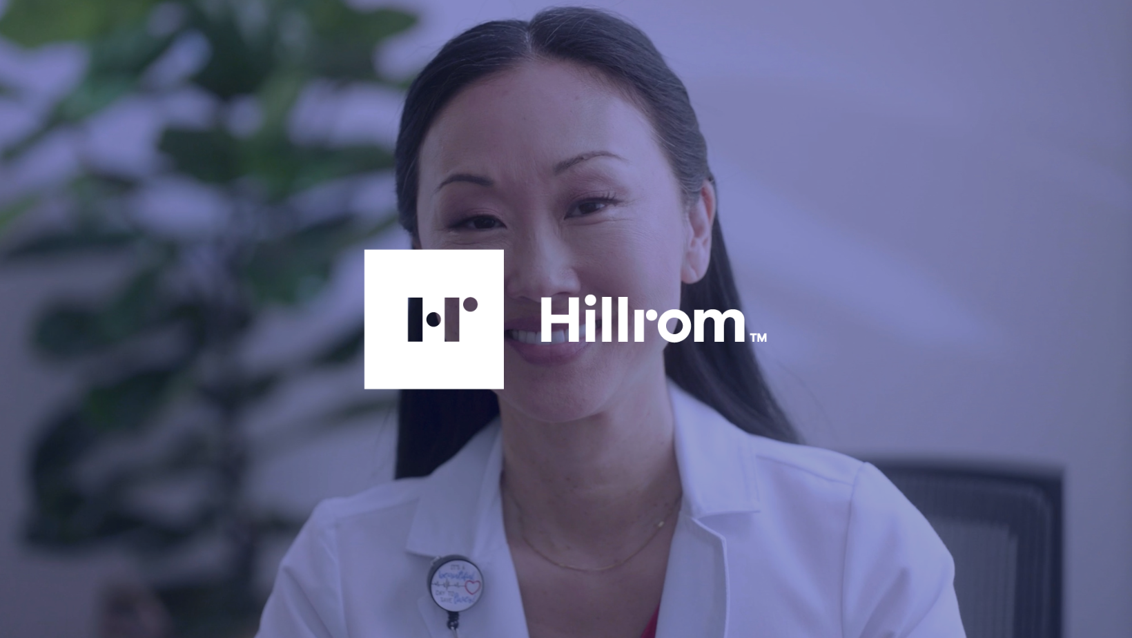 A woman wearing a white lab coat with an over lay of 'Hillrom'.