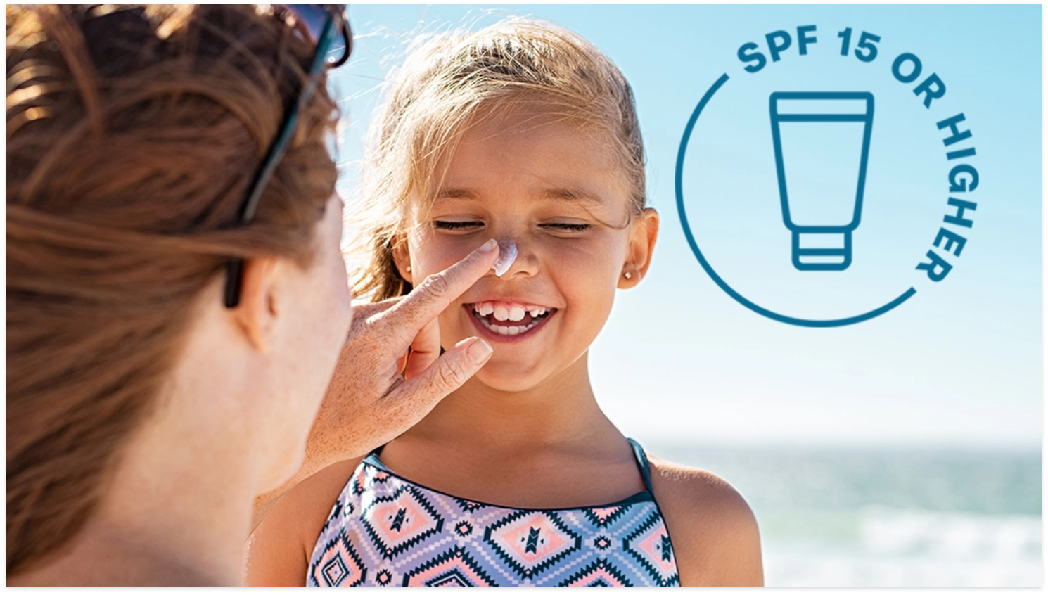 Woman playfully applying sunscreen to child's nose.