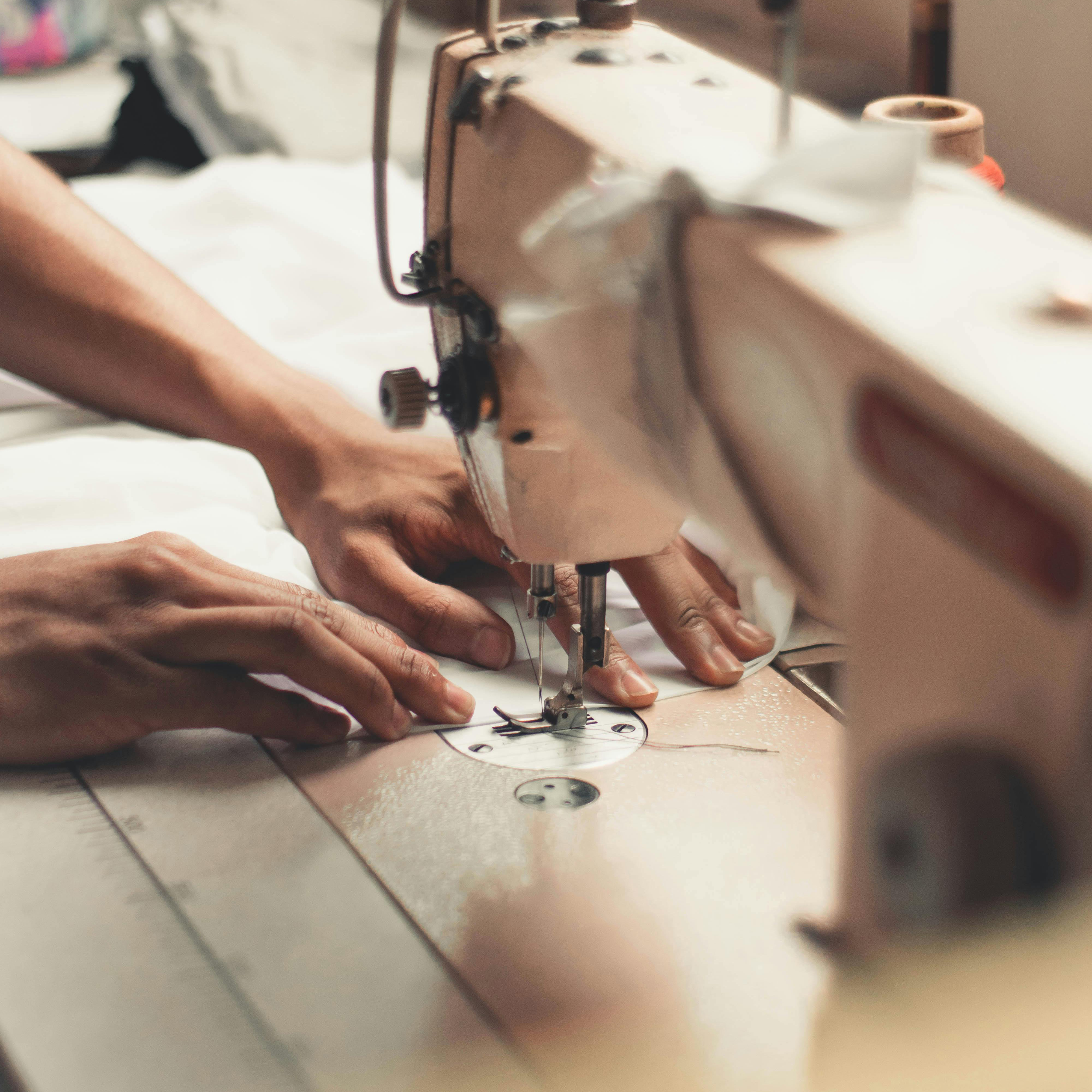 Hands sewing fabric on an industrial sewing machine.