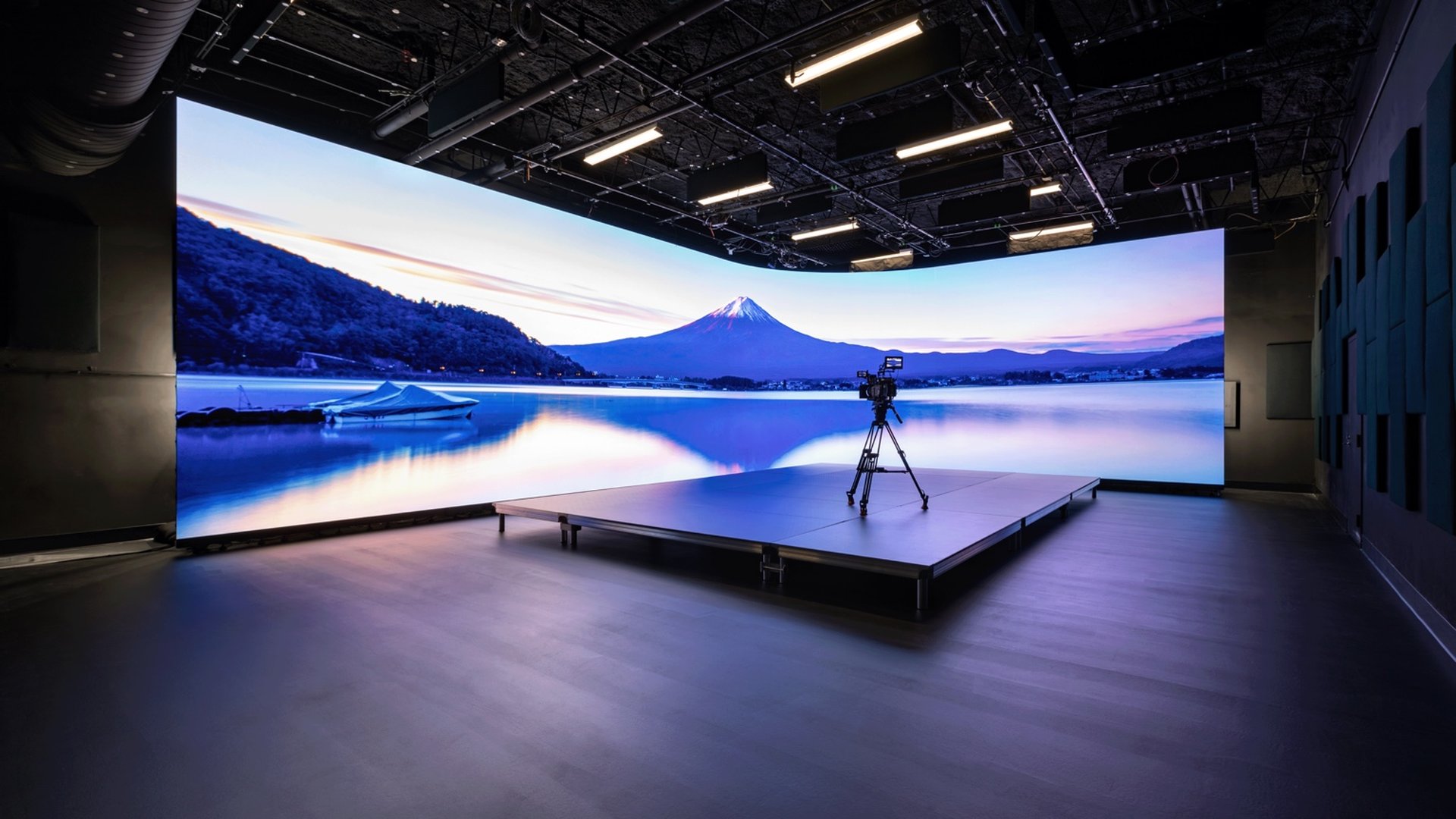 Professional studio with a curved virtual screen displaying Mount Fuji and a camera on a platform.